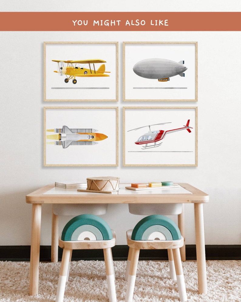 May include: Four framed illustrations of different types of aircraft, including a yellow biplane, a gray blimp, a white space shuttle, and a red helicopter. The frames are hanging on a white wall above a wooden table with two teal and white rainbow-shaped chairs.