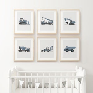 Op de afbeelding: Zes ingelijste prints van verschillende bouwvoertuigen op een witte muur. De voertuigen zijn allemaal blauw en grijs en omvatten een bulldozer, een kraan, een graafmachine, een betonmixer, een shovel en een kipper.