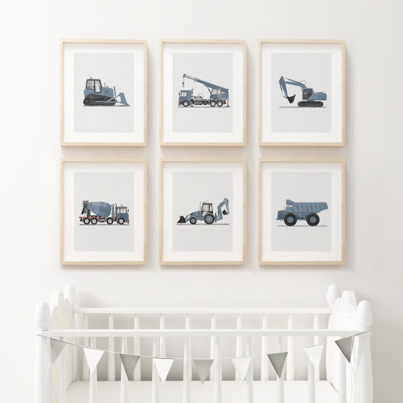 Op de afbeelding: Zes ingelijste prints van verschillende bouwvoertuigen op een witte muur. De voertuigen zijn allemaal blauw en grijs en omvatten een bulldozer, een kraan, een graafmachine, een betonmixer, een shovel en een kipper.
