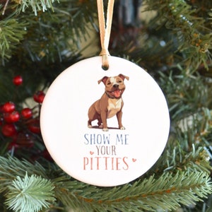 May include: White ceramic Christmas ornament with a brown and white pit bull terrier dog illustration. The ornament has the text "Show Me Your Pitties" with two red hearts.