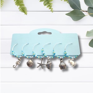 May include: Set of five blue and green beaded wine glass charms with silver seahorse, seashell, starfish, seashell, turtle and crab charms.