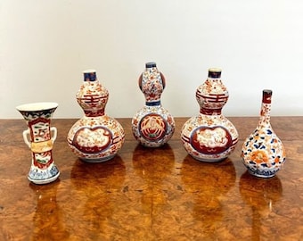May include: Five decorative ceramic vases with intricate designs in shades of blue, red, and gold. The vases are arranged on a wooden surface.