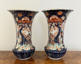 May include: A pair of tall, blue and white porcelain vases with intricate floral and landscape designs. The vases have a flared top and a rounded base.