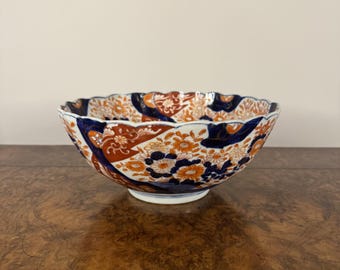 May include: A large, white ceramic bowl with a scalloped rim. The bowl is decorated with a colorful floral pattern in shades of blue, red, and orange.