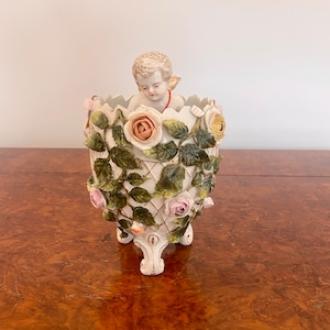 Querubín de porcelana continental de calidad victoriana antigua en un jarrón
