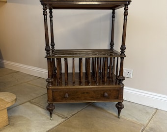May include: A dark wood magazine rack with a single drawer and a top shelf. The rack has turned legs and decorative details on the sides.