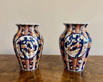 May include: A pair of blue and white porcelain vases with a floral design. The vases have a fluted shape and are decorated with gold accents.