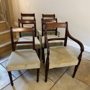 Puede incluir: Seis sillas de madera antiguas con tapicería de color verde claro. Las sillas tienen un diseño sencillo con patas torneadas y un respaldo curvo.