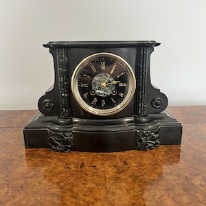 May include: A black and green marble mantel clock with Roman numeral markings on the face. The clock has gold-colored hands and a black face.