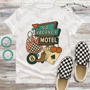 May include: White t-shirt with a retro "No Vacancy Motel" graphic. The design includes a sign, playing cards, cherries, a pool ball, and a cowboy boot. Checkered slip-on shoes are at the bottom right. Two turquoise beaded bracelets are on the left.