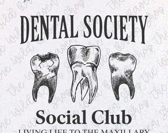 May include: A black and white graphic design featuring three teeth with the words "DENTAL SOCIETY SOCIAL CLUB" and "LIVING LIFE TO THE MAXILLARY". The Wild Raven Shop logo is at the top.