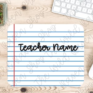 May include: A white mouse pad with blue and red lines resembling notebook paper. The text "Teacher Name" is written in black cursive on the pad.