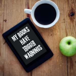 Puede incluir: Un lector electrónico negro con el texto "MY BOOKS HAVE TRIGGER WARNINGS" mostrado en la pantalla. Una manzana verde y una taza de café blanca están sobre una superficie de madera.
