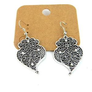 May include: A pair of silver filigree heart-shaped dangle earrings with a delicate design.
