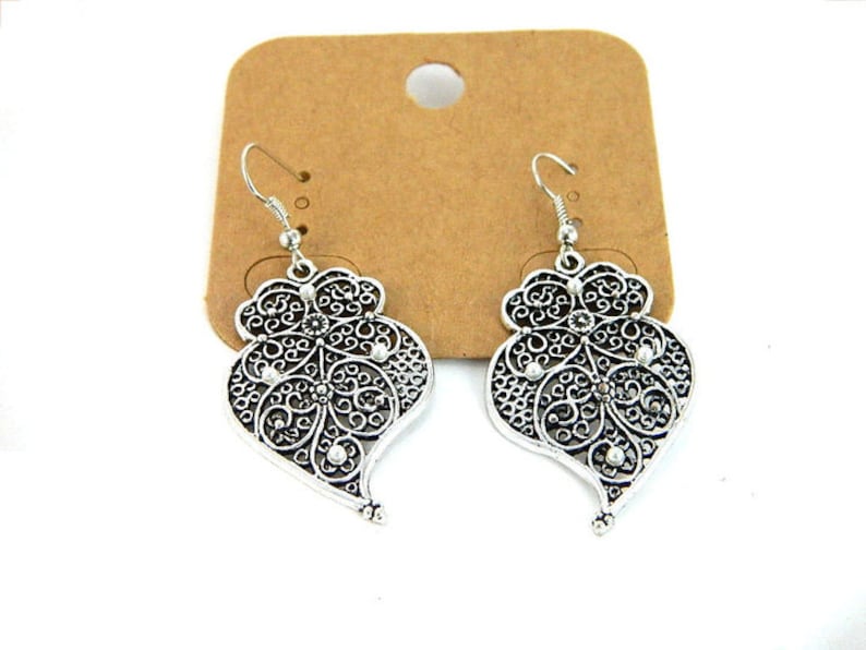 May include: A pair of silver filigree heart-shaped dangle earrings with a delicate design.