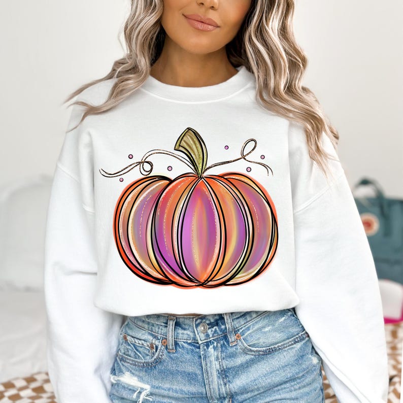 May include: White sweatshirt with a colorful, hand-drawn pumpkin design. The pumpkin has orange, pink, and purple stripes and a green stem.