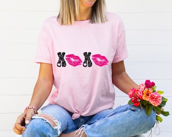 Könnte beinhalten: Ein pinkfarbenes T-Shirt mit einer schwarzen und pinkfarbenen Grafik, auf der "XOXO" mit Lippen anstelle der Os steht.