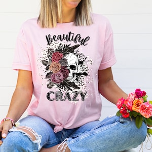 May include: Pink t-shirt with a black skull and floral design. The text "Beautiful Crazy" is printed on the shirt.