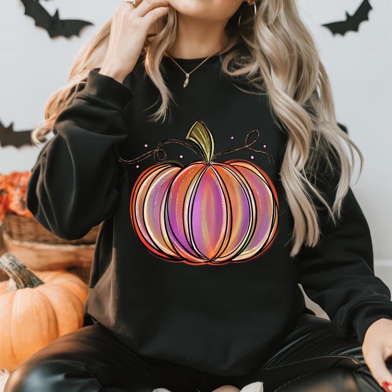 May include: Black sweatshirt with a colorful pumpkin graphic. The pumpkin is outlined in black and has a gradient of orange, pink, and purple.