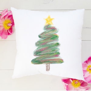 May include: White cushion with a green and gold Christmas tree painted on it. The tree is stylised and has a star on top.