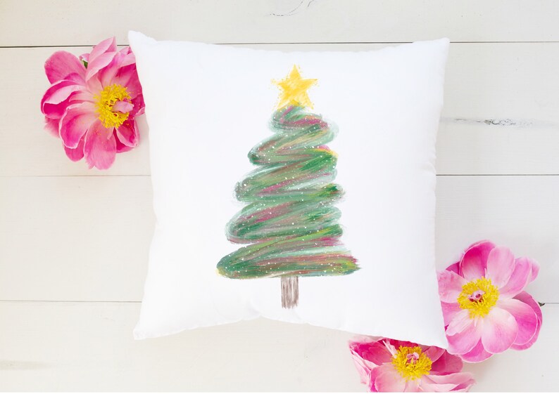 May include: White cushion with a green and gold Christmas tree painted on it. The tree is stylised and has a star on top.