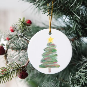 May include: White ceramic Christmas bauble with a hand-painted green Christmas tree with a yellow star on top.