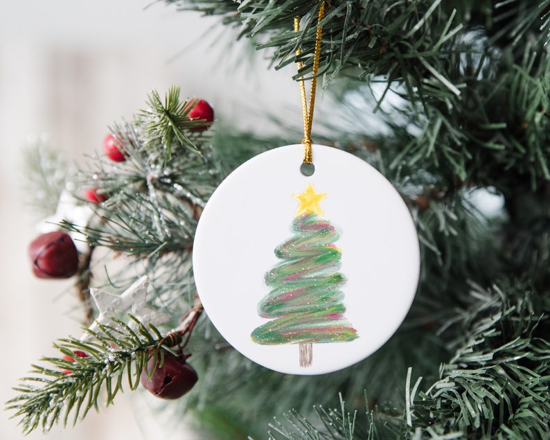 May include: White ceramic Christmas bauble with a hand-painted green Christmas tree with a yellow star on top.
