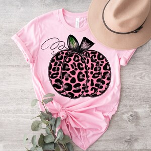 May include: Pink t-shirt with a black and pink leopard print pumpkin graphic.
