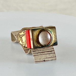 May include: A gold ring with a red and white enamel band and a round, white stone in the center.
