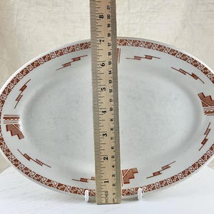May include: White oval serving platter with a brown geometric design around the edge. The platter measures 12 inches in length.