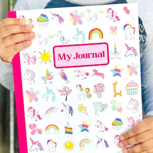 May include: A white journal with a pink border. The front cover is decorated with colorful unicorn stickers and the words 'My Journal' in a pink rectangle.