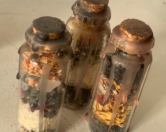 May include: Three small glass bottles filled with various dried herbs, flowers, and crystals. The bottles are sealed with cork stoppers and have a layer of wax dripped down the sides.