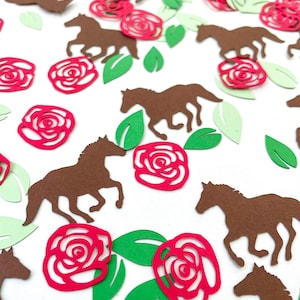 May include: Red paper roses and brown paper horses confetti. The roses have a swirl design and the horses are running.