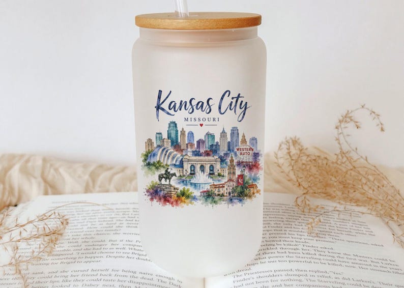 A white glass jar with a straw, featuring a colorful illustration of the skyline of Kansas City, Missouri.