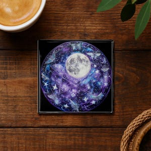 May include: Square coaster with a celestial design. The coaster features a full moon, butterflies, stars, and a pentagram against a purple and blue galaxy background. The coaster has a black border.