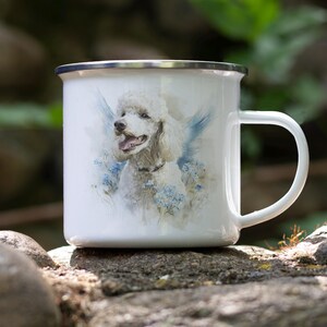 A white ceramic mug with a picture of a poodle on it, placed on a rock in a natural outdoor setting.
