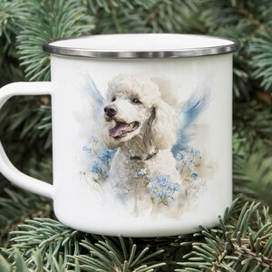 A white ceramic mug with a picture of a poodle on it, placed on top of pine needles.