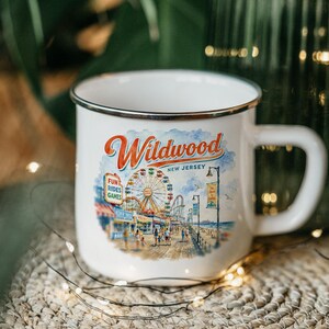 A white enamel mug with a printed design depicting a carnival scene in New Jersey.