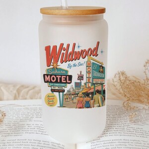 A clear glass tumbler with a straw, featuring a vintage motel sign and a vintage motel sign, placed on top of an open book.