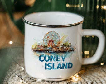 May include: White enamel mug with a Coney Island design. The mug features a watercolor illustration of the iconic Ferris wheel and boardwalk, with the words "CONEY ISLAND" in blue. The mug has a silver rim and a large handle.