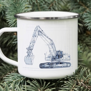 May include: White enamel mug with a silver rim featuring a blue blueprint-style illustration of an excavator. The mug has a white handle and is set against a backdrop of green pine needles.