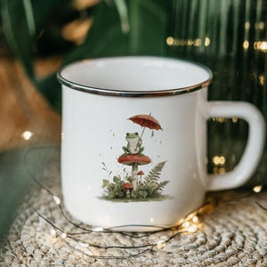May include: A white ceramic mug with a black handle and the text "But First, Coffee" in a black, bold font. The mug is sitting on a white surface. The mug is approximately 4 inches tall.