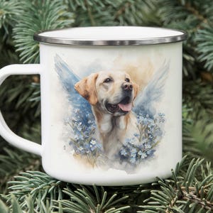 A white enamel mug with a printed image of a yellow Labrador retriever dog surrounded by blue flowers, placed on top of pine needles.