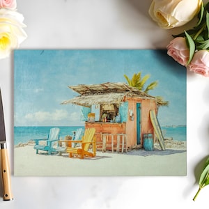 May include: A rectangular cutting board featuring a beach scene with a small orange bar, blue and yellow Adirondack chairs, and a surfboard. The scene is set on a sandy beach with a blue ocean and sky. A stainless steel knife with a light brown handle is on the left.