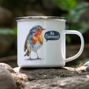 May include: White enamel mug with a watercolor illustration of a robin with orange and blue plumage. The mug has a silver rim and the words "No Comment" in a speech bubble.