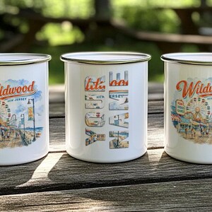 Three white mugs with colorful illustrations of a boardwalk and ferris wheel, along with the text "Wildwood NEW JERSEY" printed on them.
