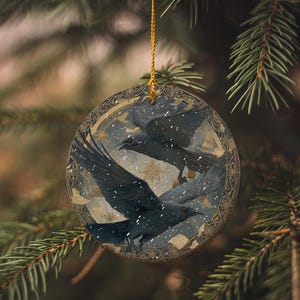 A circular ornament with a bird design hangs from a tree branch.
