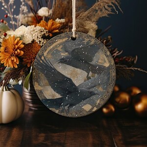 a round wooden ornament with a bird design, hanging on a wooden surface. The ornament is surrounded by a variety of autumn-themed decorations, including flowers, pumpkins, and other seasonal items.