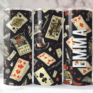 May include: Three black and white tumbler cups with a repeating pattern of playing cards, stars, and a magician's hat. The cups have the name "EMMA" printed on one of them.
