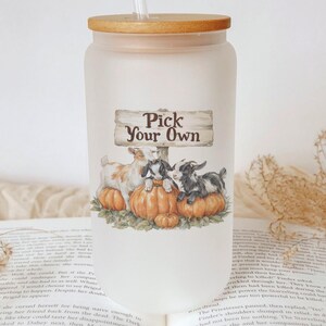 May include: A frosted glass tumbler with a wooden lid and straw. The tumbler features a whimsical illustration of goats on pumpkins with the text "Pick Your Own". The design is in warm autumn colors.